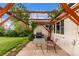 Cozy backyard patio with a wooden pergola, string lights, BBQ grill, table, and chairs at 3865 Independence Ct, Wheat Ridge, CO 80033