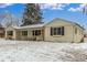 Charming single-story home with a brick facade, covered porch, and snow-covered yard at 3865 Independence Ct, Wheat Ridge, CO 80033