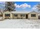 Charming single-story home with a brick facade, covered porch, and snow-covered yard at 3865 Independence Ct, Wheat Ridge, CO 80033