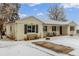 Charming single-story home with a brick facade, covered porch, and snow-covered yard at 3865 Independence Ct, Wheat Ridge, CO 80033