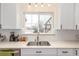 Bright kitchen featuring white cabinets, stainless sink, and a window with a neighborhood view at 3865 Independence Ct, Wheat Ridge, CO 80033