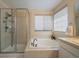 Bright bathroom features a glass-enclosed shower and a soaking tub for relaxation, with ample natural light at 10441 W Remington Dr, Littleton, CO 80127