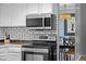 Kitchen with stainless steel microwave and stove, subway tile backsplash, and dining area view at 3767 E Phillips Cir, Centennial, CO 80122