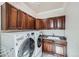 Laundry room with updated washer and dryer, wood cabinetry, and a utility sink at 9182 Ridgegate Pkwy, Lone Tree, CO 80124