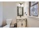 Charming powder room features decorative mirror, pedestal sink, and stained glass window for added elegance at 9182 Ridgegate Pkwy, Lone Tree, CO 80124