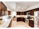 Modern kitchen featuring stainless steel appliances, dark wood cabinets, granite countertops, and tile floors at 1941 Fox Fire St, Highlands Ranch, CO 80129