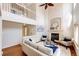 Open-concept living room with a fireplace, hardwood floors, a ceiling fan, and a view of the upper level at 1941 Fox Fire St, Highlands Ranch, CO 80129