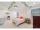 Bright bedroom with white walls, decorative ceiling vine, and a cozy bed with pink linens and gold mirror at 21434 E Greenwood Pl, Aurora, CO 80013