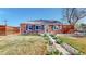 Charming brick home featuring a well-maintained lawn with a walkway lined with plants and dark window shutters at 7785 E 13Th Ave, Denver, CO 80220