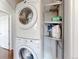 Laundry area with stacked washer and dryer, shelves, and open doorway to another room at 7785 E 13Th Ave, Denver, CO 80220