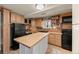 Traditional kitchen featuring wooden cabinets, black appliances, butcher block island, and tile backsplash at 2041 Virginia St, Idaho Springs, CO 80452