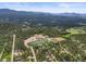 Aerial view showcases community school, athletic field, mountain views, and surrounding wooded neighborhood at 26499 West St, Conifer, CO 80433