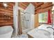 Bathroom showcasing a soaking tub, walk-in shower with stone accents, and double sink vanity at 26499 West St, Conifer, CO 80433