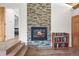 Inviting living area featuring a stone fireplace, wood flooring, and adjacent bookshelf, creating a cozy atmosphere at 26499 West St, Conifer, CO 80433