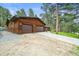 Spacious three-car garage attached to a wood-sided house, perfect for car enthusiasts or extra storage at 26499 West St, Conifer, CO 80433