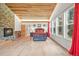 Bright main bedroom with a stone fireplace, wood ceiling, and a wall of windows offering serene views at 26499 West St, Conifer, CO 80433