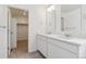 Modern bathroom featuring double sinks, sleek cabinets, a large mirror and access to walk-in closet at 760 N Deer Park St, Watkins, CO 80137