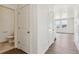 Hallway featuring laminate floors, white doors, and a half bath, creating a bright, clean aesthetic at 760 N Deer Park St, Watkins, CO 80137