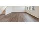 Open-concept living room featuring laminate flooring, large windows, and access to stairs at 760 N Deer Park St, Watkins, CO 80137