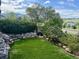 Beautiful backyard view with lush landscaping and a rock water feature overlooking a lake in the distance at 10565 Kicking Horse Dr, Littleton, CO 80125