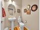 Cozy half-bathroom features pedestal sink, toilet, hardwood floors, and decorative wall art at 10565 Kicking Horse Dr, Littleton, CO 80125
