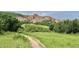 Beautiful natural landscape with a walking path through a lush green meadow, leading to striking red rock formations at 10565 Kicking Horse Dr, Littleton, CO 80125