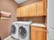 Well-organized laundry room with washer, dryer, sink, and ample overhead cabinet storage at 10565 Kicking Horse Dr, Littleton, CO 80125