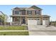 A daytime view of a two-story home showcasing a covered front porch and three-car garage at 7702 E 159Th Ave, Thornton, CO 80602