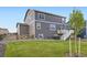 Beautiful gray home with a green lawn, a wooden fence, and a wooden staircase with a white banister at 7702 E 159Th Ave, Thornton, CO 80602