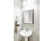 Well-lit powder room featuring a pedestal sink, framed mirror, modern fixtures, and decorative towel at 16300 Paris Way, Brighton, CO 80602