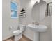Modern powder room featuring a pedestal sink, round mirror, and stylish decor at 3888 Grand Baker St, Aurora, CO 80019