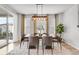 Bright dining room features modern chandelier, large windows, and seating for six at 14066 Ivanhoe Ct, Thornton, CO 80602