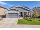 Charming single-story home featuring well-kept lawn, inviting porch, gray siding, and a two-car garage at 14066 Ivanhoe Ct, Thornton, CO 80602