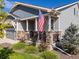 Inviting front porch with stone pillars, lush landscaping, and charming decorative touches at 14066 Ivanhoe Ct, Thornton, CO 80602