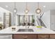Bright, open kitchen with a large island, stainless steel sink, and modern pendant lighting above the island at 14066 Ivanhoe Ct, Thornton, CO 80602