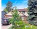 Two-story home with a brick and siding exterior, mature trees, well-maintained lawn and landscaping with a grey car parked in driveway at 7217 S Zephyr Way, Littleton, CO 80128