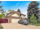 Charming two-story home with a brick and siding exterior, mature trees, and a well-maintained lawn and a grey car parked in driveway at 7217 S Zephyr Way, Littleton, CO 80128