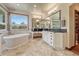Serene bathroom featuring dual sinks, a soaking tub, and large mirrors and windows at 5275 Pinyon Jay Rd, Parker, CO 80134