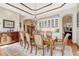 Elegant dining room with tray ceiling, a large table, and an adjacent sideboard with glass-front cabinets at 5275 Pinyon Jay Rd, Parker, CO 80134