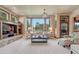 Comfortable living room with stone fireplace and a large window overlooking the greenery of the backyard at 5275 Pinyon Jay Rd, Parker, CO 80134