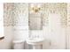Bright bathroom featuring floral wallpaper, a pedestal sink, and vintage-style lighting at 650 Kearney St, Denver, CO 80220