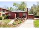 Cozy red brick home with green lawn, lush trees, garden and driveway to a detached garage at 650 Kearney St, Denver, CO 80220
