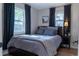 Comfortable bedroom featuring soft gray bedding, two windows, and dark curtains for a restful atmosphere at 134 S Quitman St, Denver, CO 80219