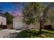 Inviting front exterior showcasing a well-manicured lawn and mature tree providing shade with dusk sky at 1232 Bluebird St, Brighton, CO 80601