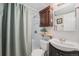 Bathroom featuring a shower with a green curtain, toilet, and vanity with storage at 6513 Gray St, Arvada, CO 80003