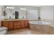 Bathroom featuring dual sinks, a soaking tub, tile flooring, and a glass block window at 688 Cinnabar Ln, Castle Rock, CO 80108