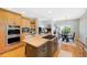 Open kitchen with cooktop island, seating, double oven, and views into the dining and living areas at 85 Willowleaf Dr, Littleton, CO 80127