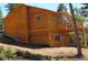 View of the home's back with wooden siding, showing a walkout basement, a small truck and lush trees at 10178 Hutch Ln, Conifer, CO 80433