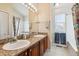 Bathroom featuring double sinks with granite countertops, large mirror, and tub with shower at 7641 Lebrun Ct, Lone Tree, CO 80124