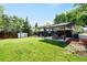 A spacious backyard features a covered patio, lush green lawn, and a convenient storage shed at 6512 Upham St, Arvada, CO 80003
